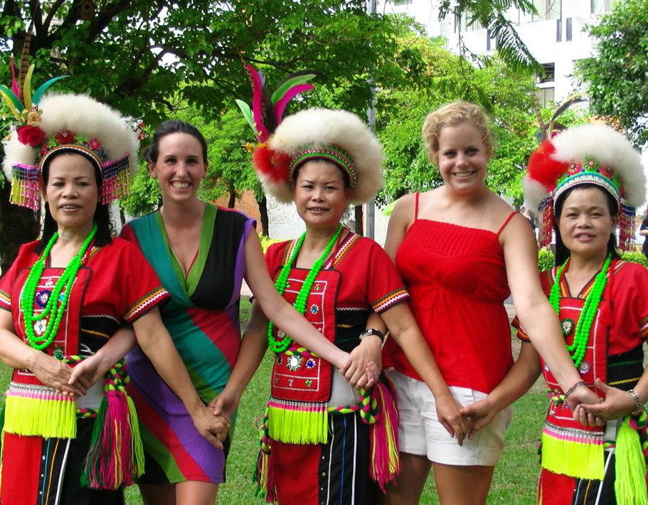 photo: Two foreign students dance with three Taiwanese aborigines wearing traditional clothes.